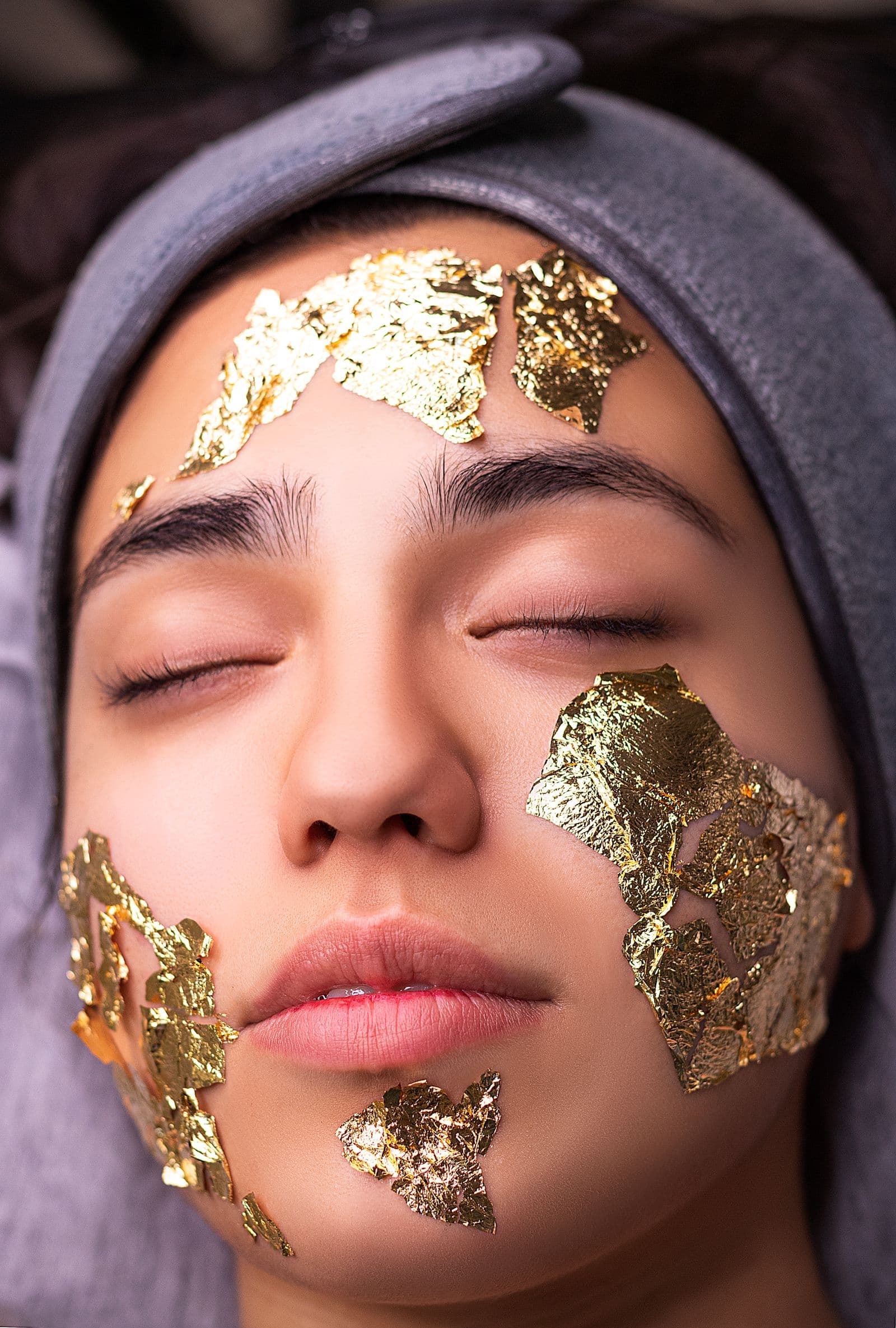 An editorial beauty portrait with a gold-leaf facial mask